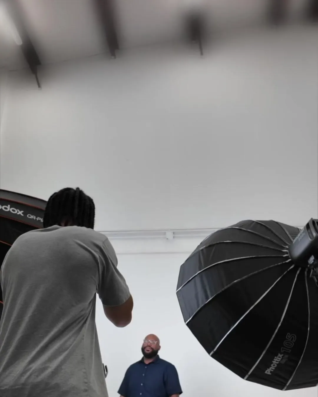 Photographer shooting a client against a white studio backdrop with a large softbox