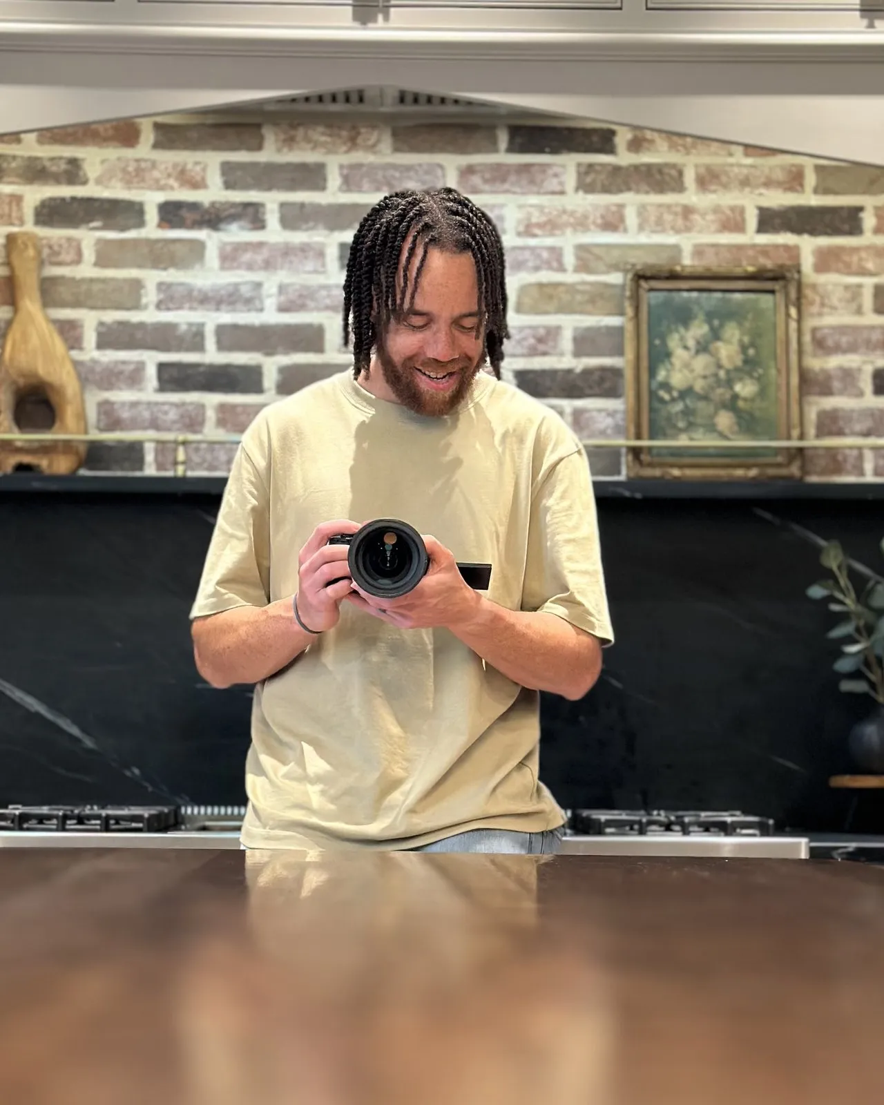 Tyler Thompson smiling at a table, holding a camera